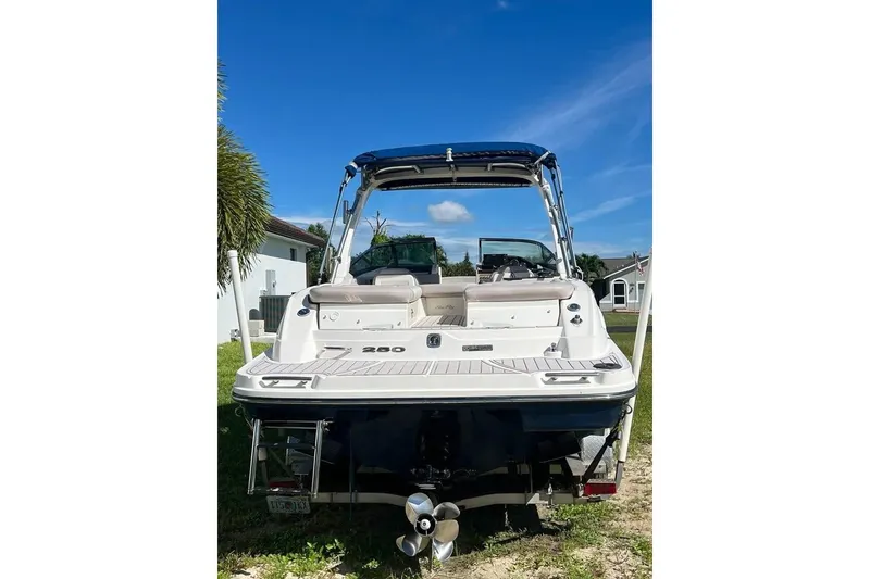 Slide: The Image of 2012 Sea Ray 250 SLX boat, rear view, parked on grass under clear blue sky. - 3