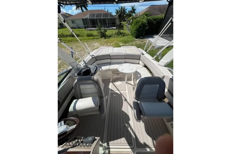 Slide: The Image of 2012 Sea Ray 250 SLX boat interior with seating and table, docked near greenery. - 5
