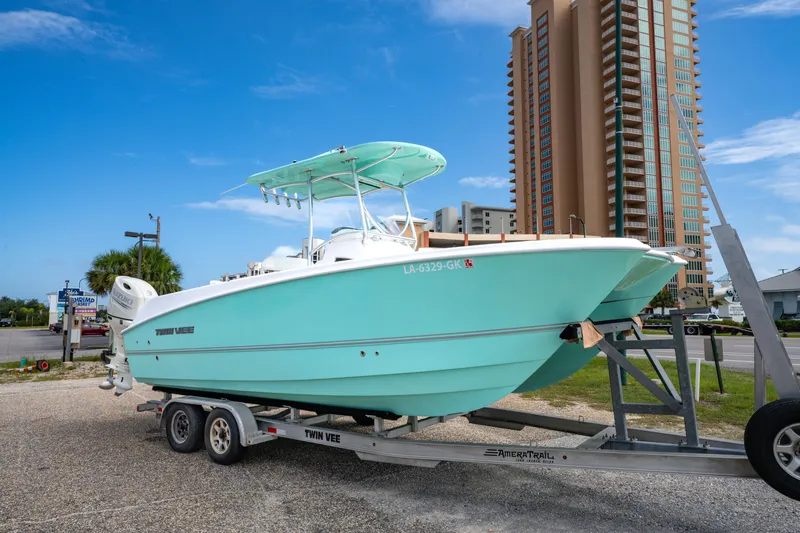 Slide: The Image of 2019 Twin Vee 240 GFX CC boat on trailer, parked near tall building. - 1