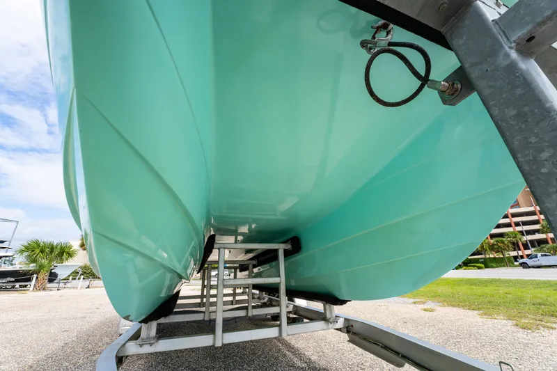 Slide: The Image of 2019 Twin Vee 240 GFX CC boat hull on trailer, turquoise color, outdoor setting. - 14