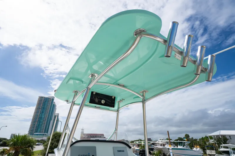 Slide: The Image of 2019 Twin Vee 240 GFX CC boat with teal canopy and rod holders, marina background. - 16