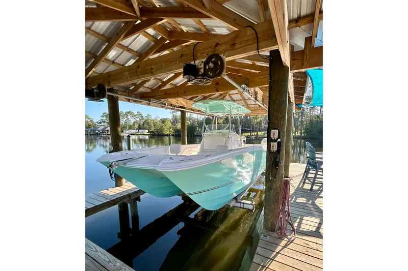 Slide: The Image of 2019 Twin Vee 240 GFX CC boat docked under wooden shelter by a serene lake. - 5