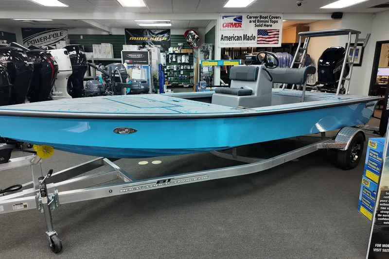 The Image of 2026 Xpress Skiff 185 in showroom, blue hull, on trailer, surrounded by boating equipment. - 0