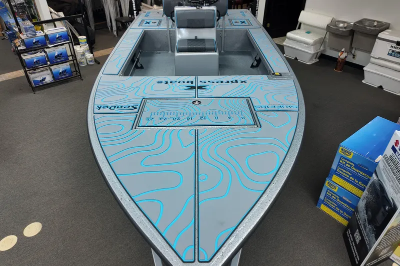 Slide: The Image of 2026 Xpress Skiff 185 boat with blue contour design in showroom. - 11