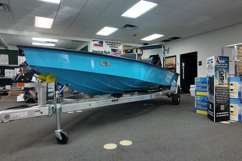 Slide: The Image of 2026 Xpress Skiff 185 boat displayed indoors on a trailer. - 2
