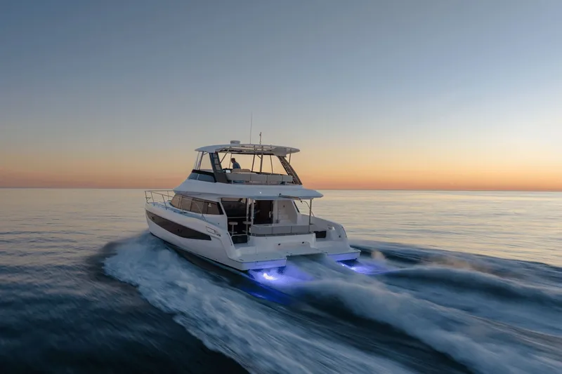 Slide: The Image of The 2027 Aquila A42Y cruises on calm waters at sunset, featuring glowing lights. - 3