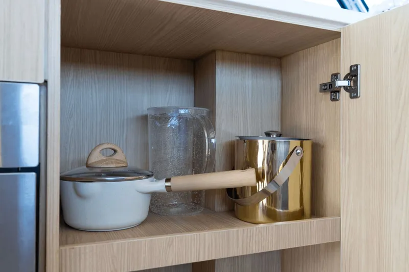 Slide: The Image of An open wooden cabinet with a white pot, a gold bucket, and a glass pitcher. - 48