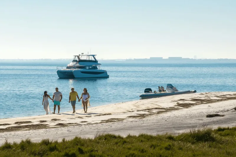 Slide: The Image of A 2027 Aquila A42Y is anchored in calm waters as four people walk along the beach. - 7