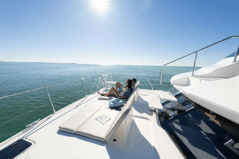 Slide: The Image of Two people relax on the deck of a 2027 Aquila A42Y yacht under bright sunshine. - 25