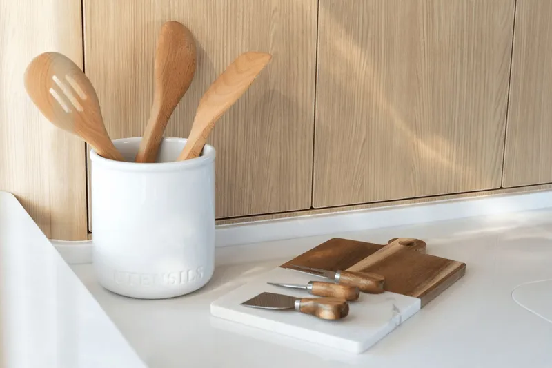 Slide: The Image of Modern kitchen with wooden utensils and cutting boards on a white countertop. - 42