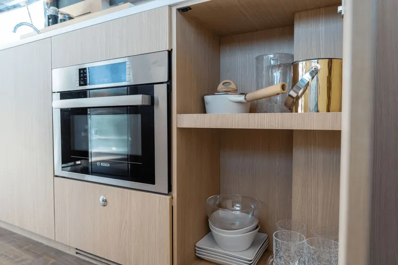 Slide: The Image of Modern onboard kitchen with wooden cabinets, built-in oven, and glassware. - 46