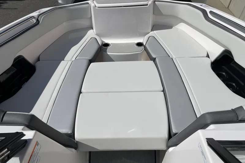 Slide: The Image of 2025 Yamaha Boats AR250 interior seating with cup holders, featuring sleek gray and white upholstery. - 11