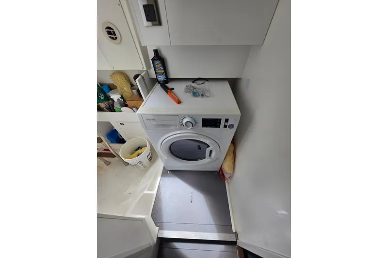 Slide: The Image of Laundry area with a white washing machine, cleaning supplies, and a bucket on the floor. - 26