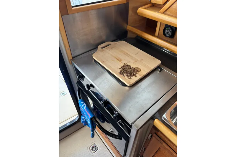 Slide: The Image of Kitchen area of a 2013 Cutwater C-28 boat with stove and cutting board. - 6
