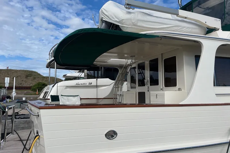 Slide: The Image of 2007 Fleming 55 yacht docked, featuring elegant design and green canopy under a blue sky. - 12