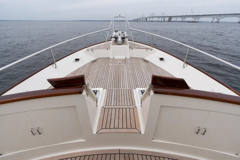 Slide: The Image of 2007 Fleming 55 yacht deck with wooden finish, bridge in background over calm water. - 20