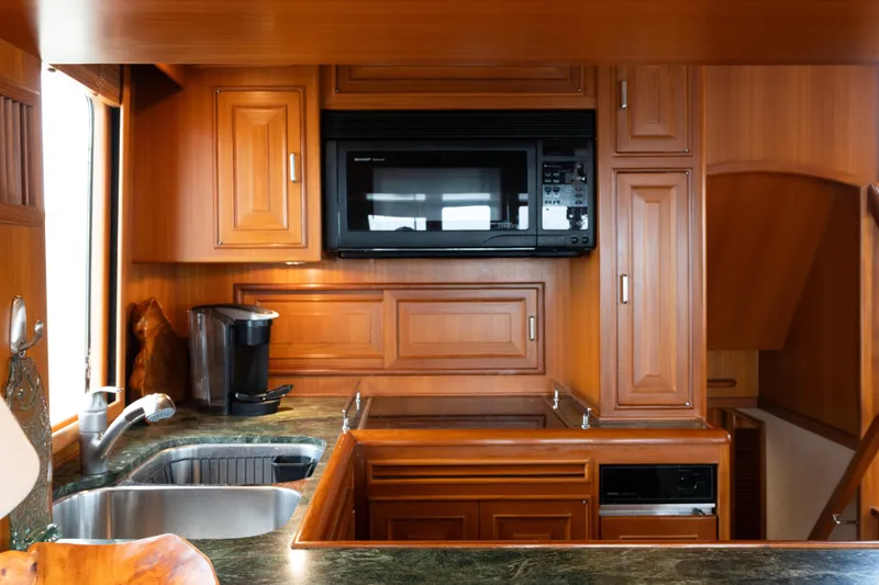 Slide: The Image of Luxurious wood-finished kitchen in a 2007 Fleming 55 yacht, featuring modern appliances. - 42