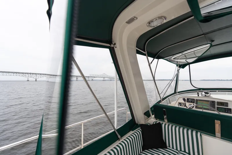 Slide: The Image of Luxurious 2007 Fleming 55 yacht with striped seating, cruising near a bridge on calm waters. - 84