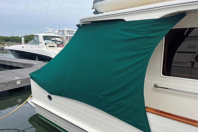 Slide: The Image of 2007 Fleming 55 yacht docked, featuring green covers and a tender on top. - 97