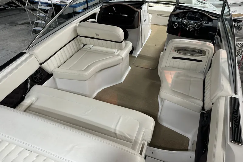 Slide: The Image of Interior of a 2012 Cobalt A25 boat with white leather seating and modern dashboard. - 16