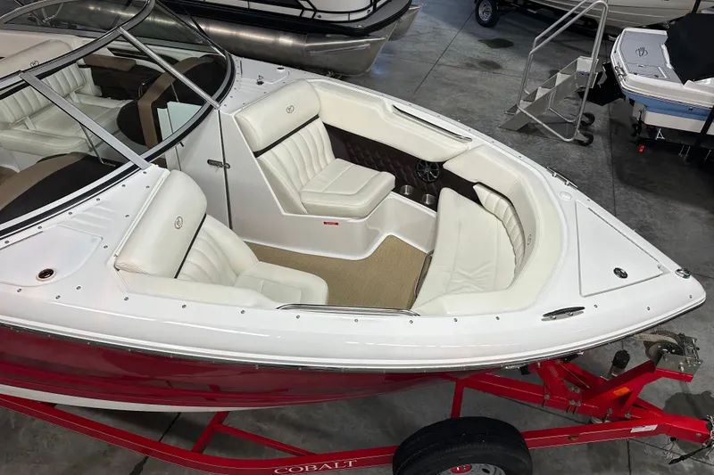 Slide: The Image of 2012 Cobalt A25 boat with white leather seating and red trailer in showroom. - 3