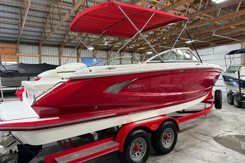 Slide: The Image of 2012 Cobalt A25 boat with red hull and canopy on trailer in storage facility. - 4