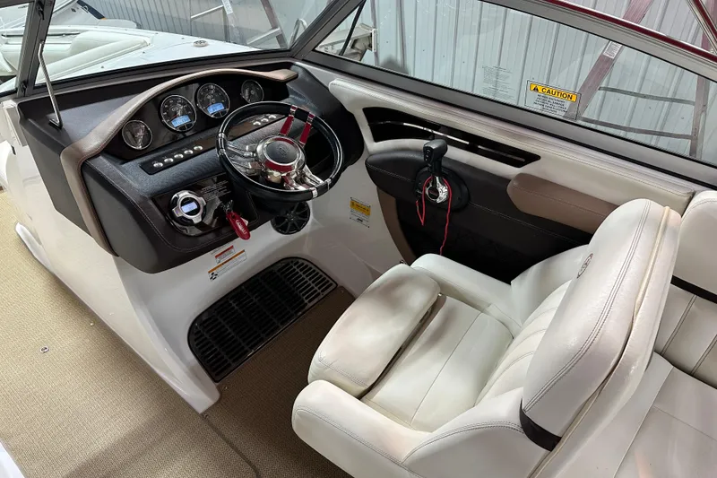 Slide: The Image of 2012 Cobalt A25 boat cockpit with steering wheel, gauges, and white seating. - 7