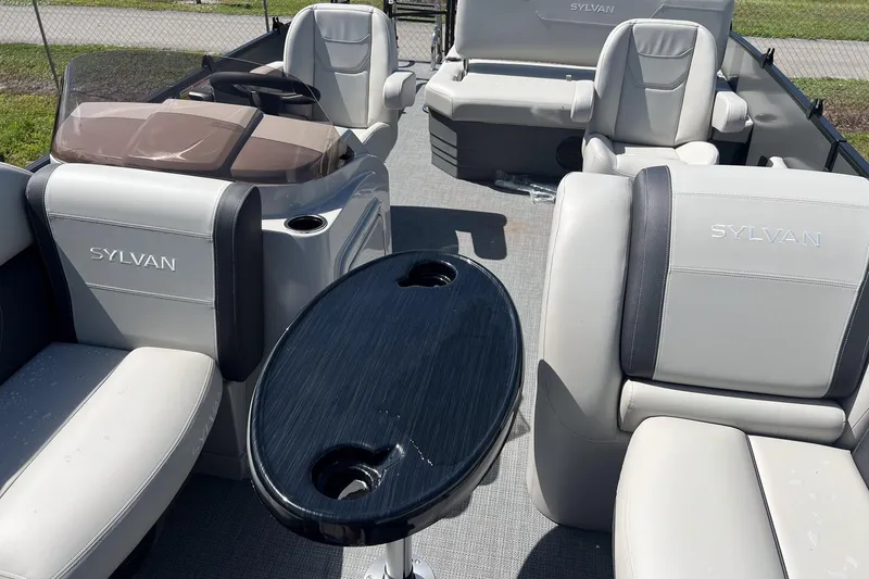 Slide: The Image of 2026 Sylvan Mirage 820 CLZ DH pontoon boat interior with plush seating and sleek table. - 6