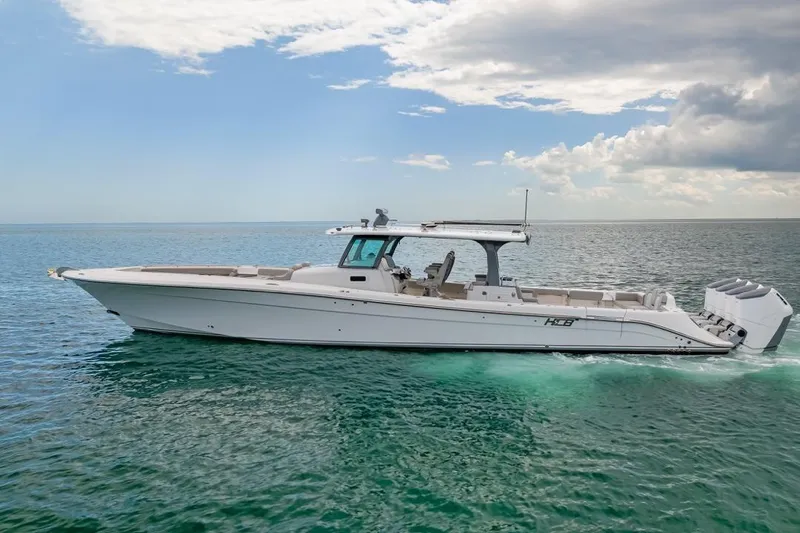 The Image of 2023 HCB 53 Sueños boat cruising on open water under a partly cloudy sky. - 1