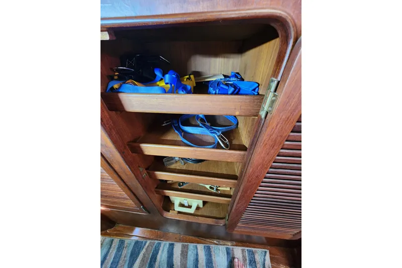 Slide: The Image of Wooden cabinet with shelves storing blue and yellow straps on a 1981 Guflstar Center Cockpit. - 45