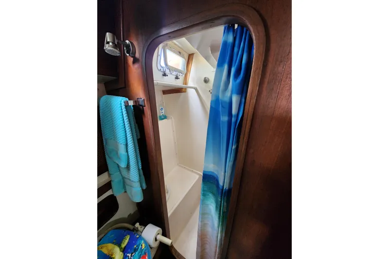 Slide: The Image of 1981 Guflstar Center Cockpit bathroom with shower, blue towel, and ocean-themed curtain. - 63