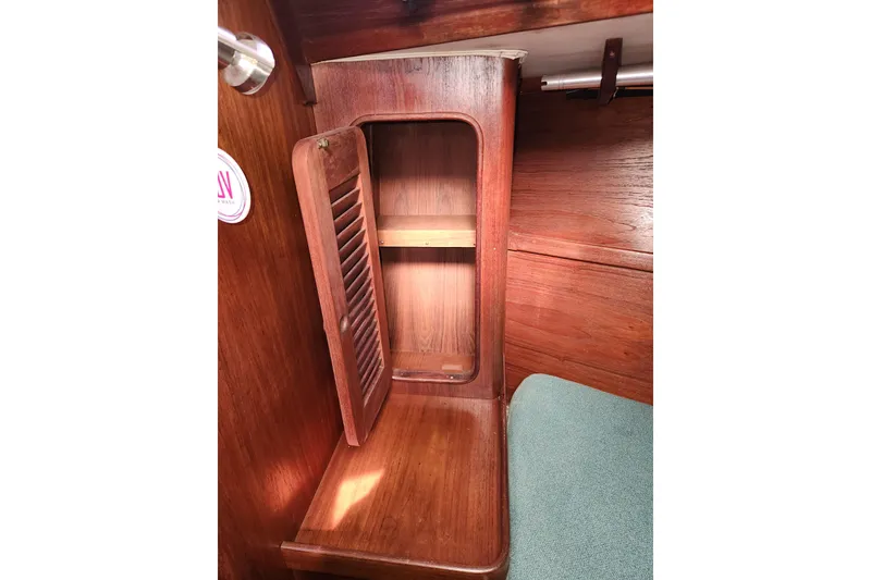 Slide: The Image of 1981 Gulfstar Center Cockpit interior with open wooden cabinet and green cushion. - 72