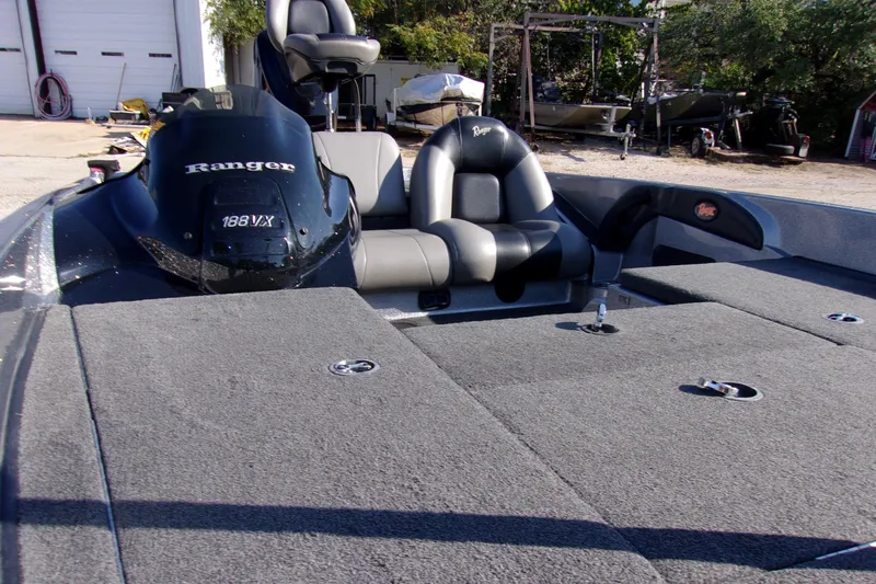 Slide: The Image of 2009 Ranger 188 VX boat interior with seating and motor, parked outdoors. - 10