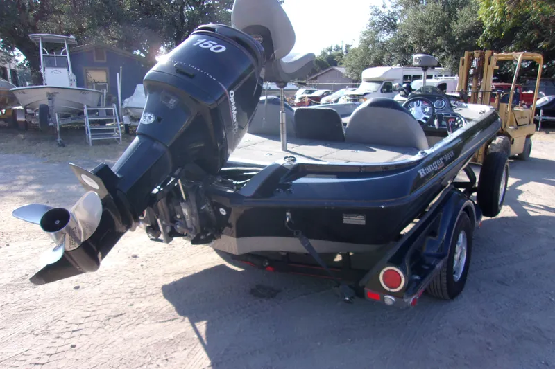 Slide: The Image of 2009 Ranger 188 VX boat with outboard motor, parked on a trailer in a yard. - 3