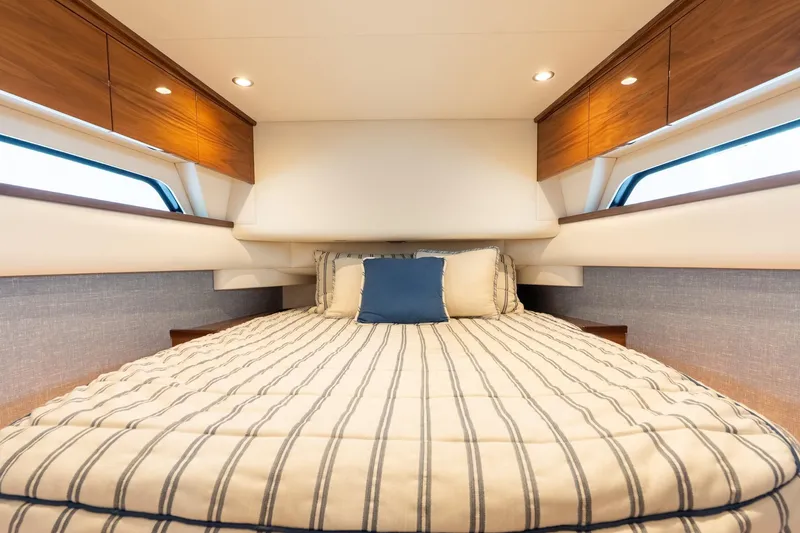 Slide: The Image of Luxurious cabin interior of 2025 Valhalla Boatworks V-55 with striped bedding and wooden cabinets. - 32