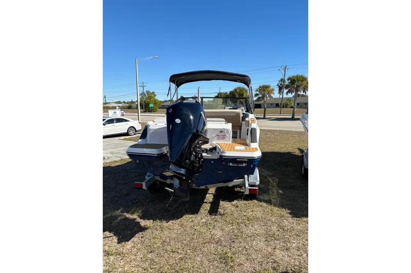 Slide: The Image of 2026 Trophy T22SC boat with outboard motor, parked on grass under clear blue sky. - 7
