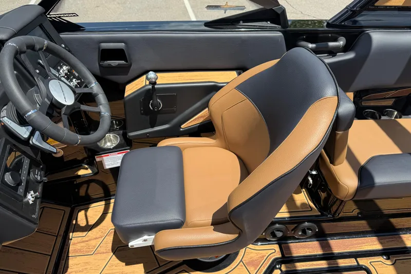 Slide: The Image of 2025 Moomba Tykon interior with tan and black seating, steering wheel, and wood accents. - 10