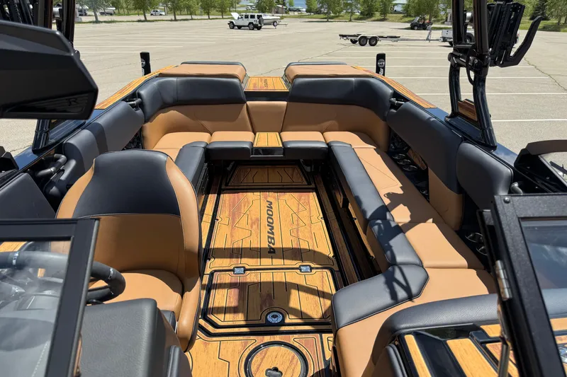 Slide: The Image of 2025 Moomba Tykon boat interior with tan and black seating, parked in a lot. - 11