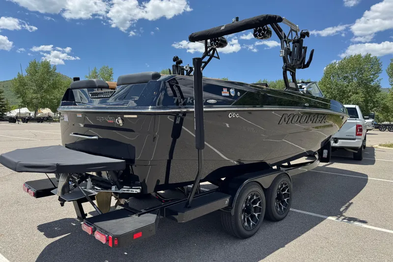 Slide: The Image of 2025 Moomba Tykon boat on trailer in sunny parking lot. - 2