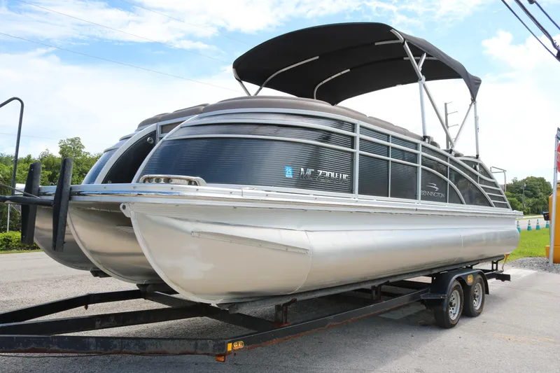 The Image of 2018 Bennington 23 QCW pontoon boat on trailer, featuring sleek design and canopy. - 0