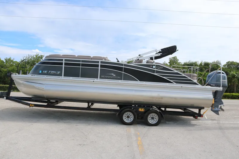 Slide: The Image of 2018 Bennington 23 QCW pontoon boat on trailer, parked outdoors. - 2