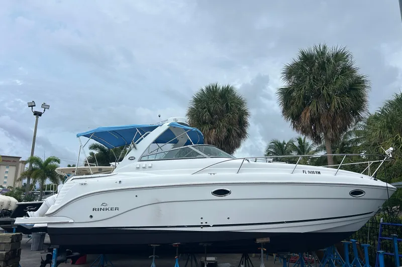 The Image of 2007 Rinker 300 Fiesta Vee boat with blue canopy, docked near palm trees. - 0