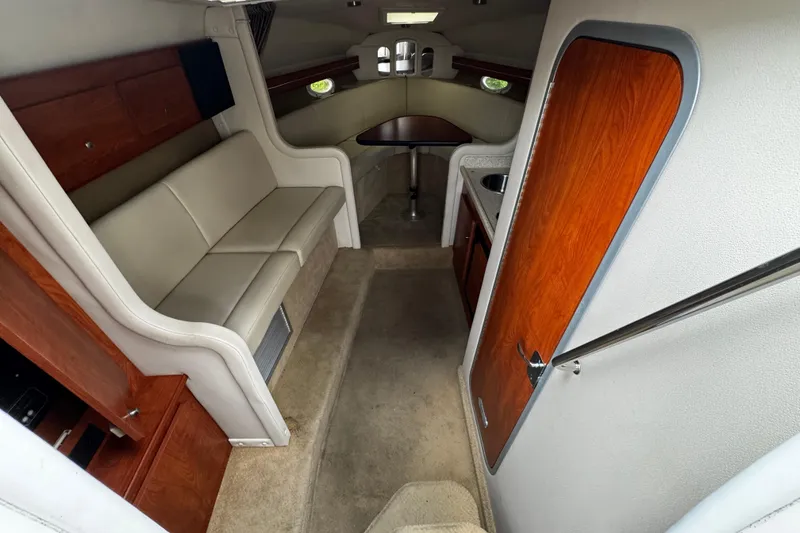 Slide: The Image of 2007 Rinker 300 Fiesta Vee interior with beige seating, wooden accents, and compact kitchenette. - 21