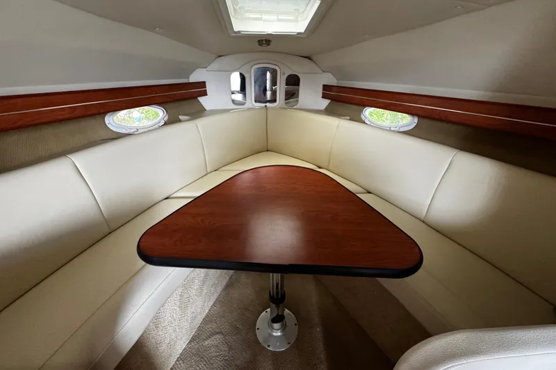 Slide: The Image of 2007 Rinker 300 Fiesta Vee cabin interior with wood table and beige seating. - 25