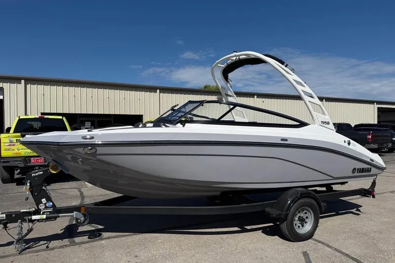The Image of 2026 Yamaha Boats 195S on trailer, parked outdoors under clear blue sky. - 0