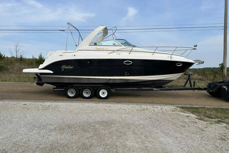 The Image of 2003 Rinker Fiesta Vee 290 boat on trailer, parked roadside under clear sky. - 0