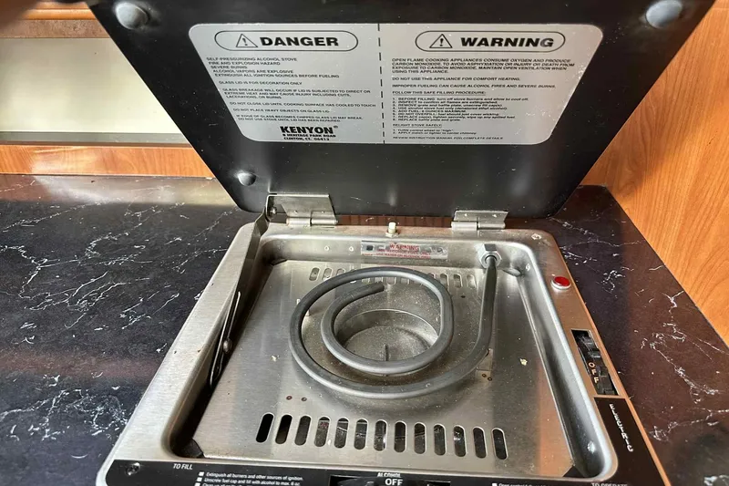 Slide: The Image of 2003 Rinker Fiesta Vee 290 stove with safety warnings and electric coil burner. - 17