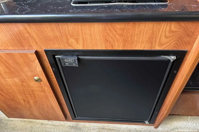 Slide: The Image of 2003 Rinker Fiesta Vee 290 interior with Tundra fridge and wood cabinetry. - 18