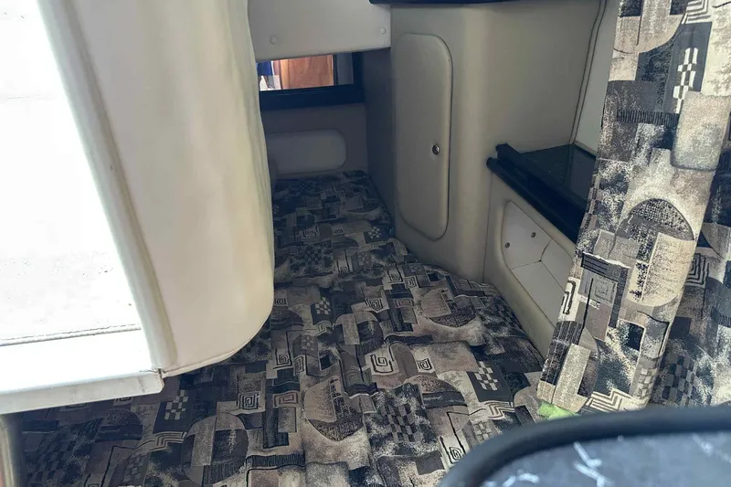 Slide: The Image of 2003 Rinker Fiesta Vee 290 cabin interior with patterned upholstery and storage compartments. - 19