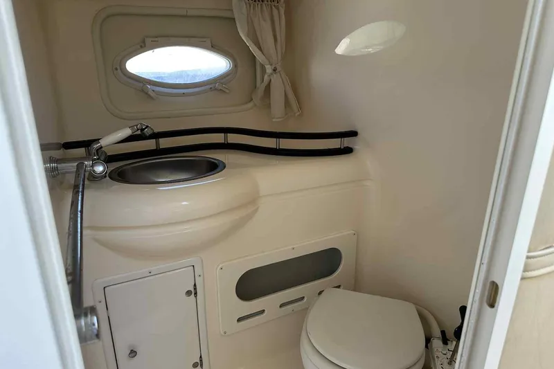 Slide: The Image of 2003 Rinker Fiesta Vee 290 boat bathroom with sink, toilet, and porthole window. - 3